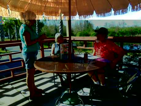 Guests enjoying food and drinks under the thatched tiki hut at WingNutz beside Lake Bryant